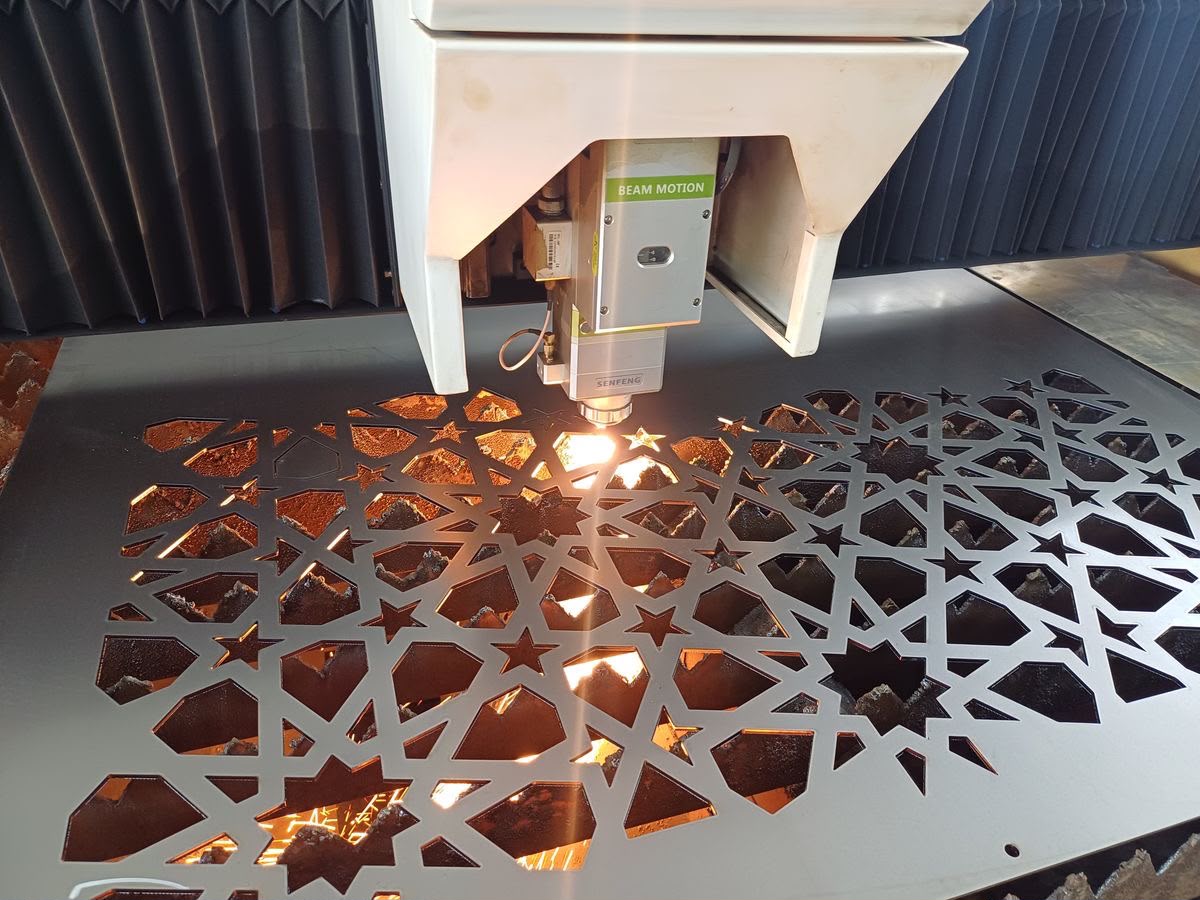 Close-up of a geometric star pattern being laser cut into sheet metal
