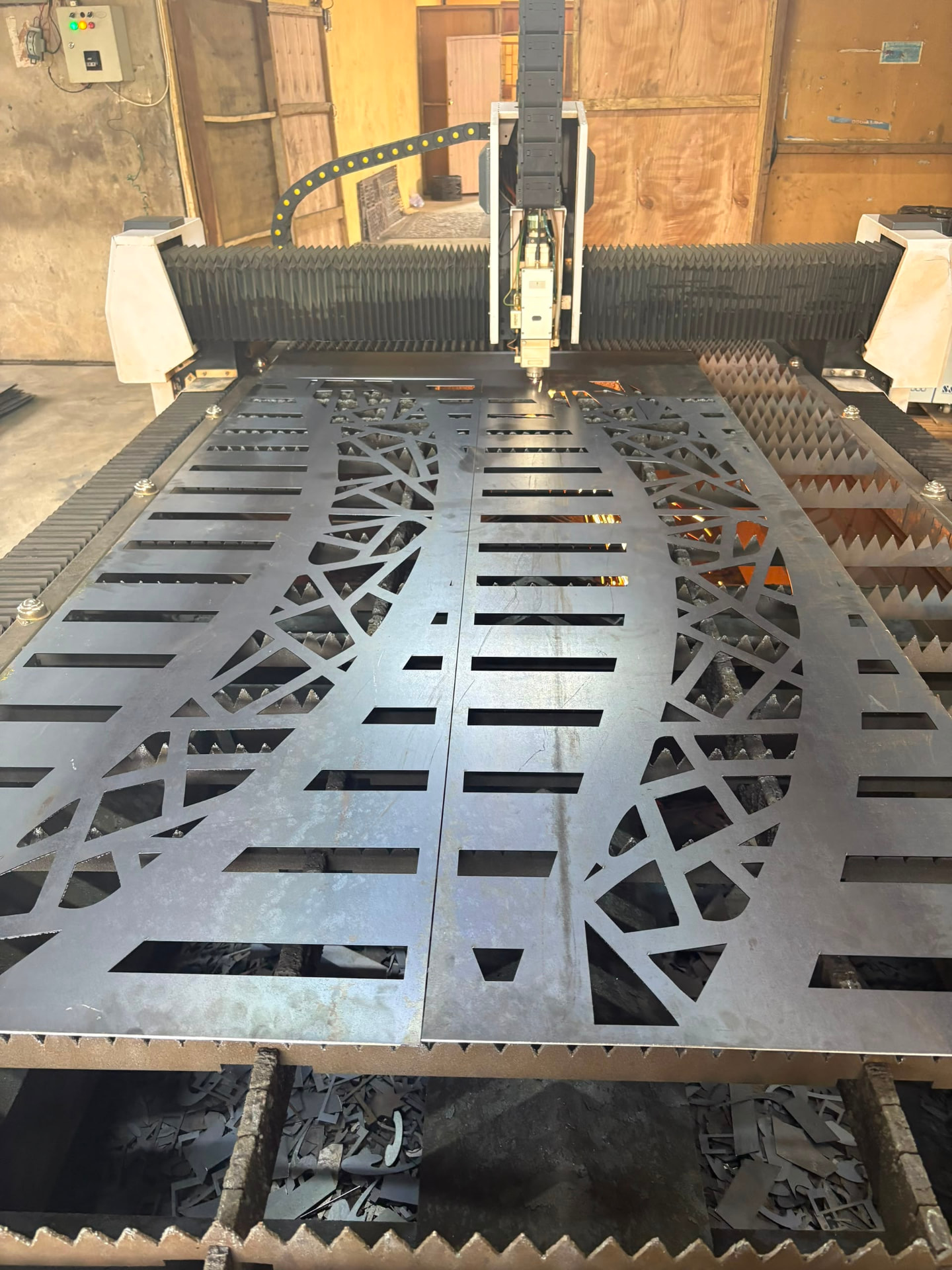 Large laser-cut steel panel with a custom architectural pattern on the machine bed